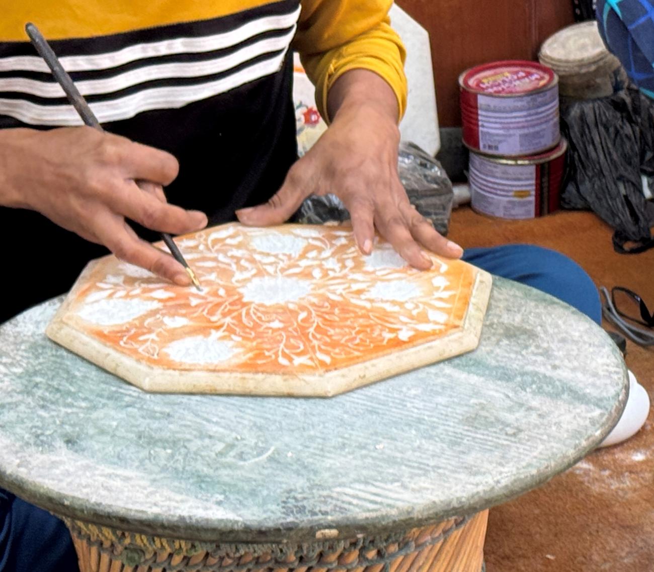 A man in India using the art of Pietra Dura to form geometric patterns on stone