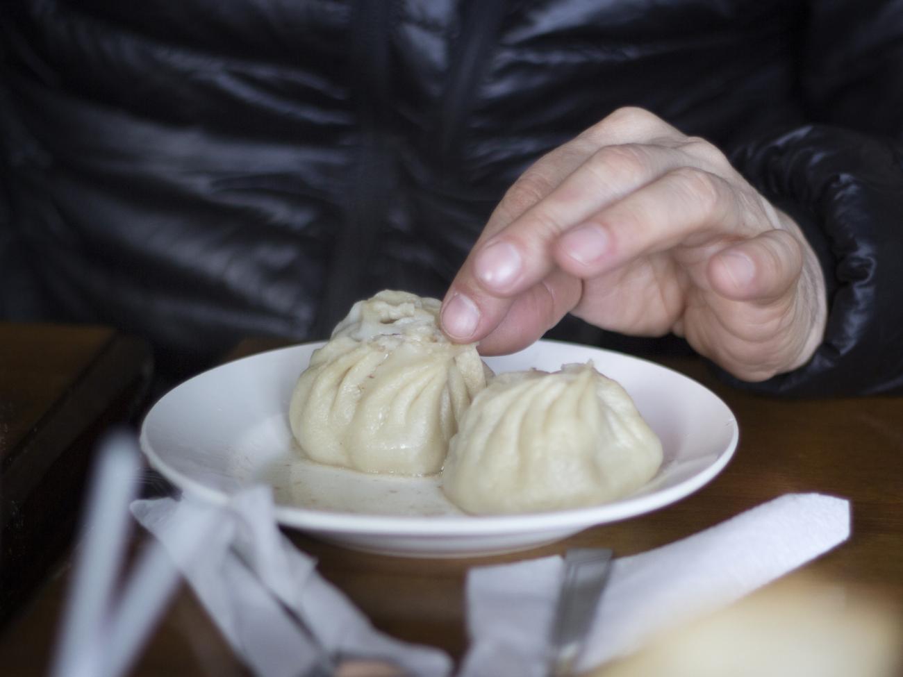 Close up of hands and Mongolian dumplings on a plate called Buuz